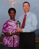 Loretta and Matthew B. Aaron holding a trophy together as fireworks light the sky