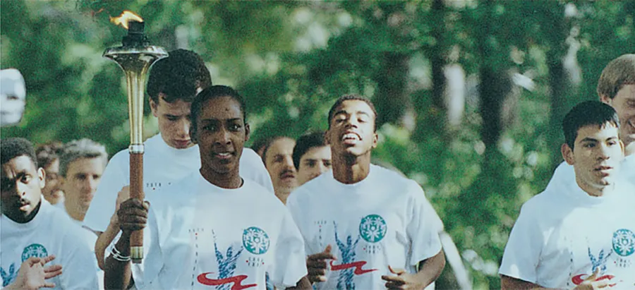 Loretta running with young torch runners in matching Special Olympics T-shirts