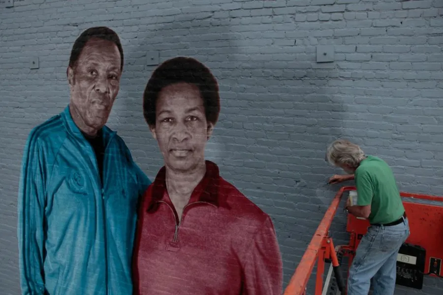 Mural of Rafer Johnson and Loretta in Los Angeles, with an artist at work beside it