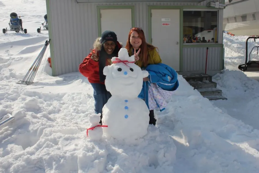 Loretta and a friend posing beside a snowman