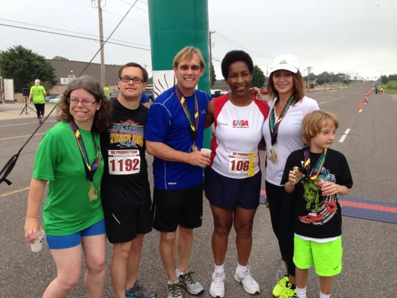 Loretta with fellow runners and a young boy after a race, all wearing finisher medals