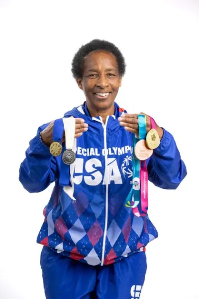 Loretta in a Special Olympics USA jacket holding up her medals
